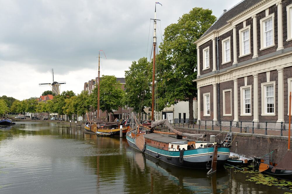 De Schiedamse haven met historische schepen langs de kade en een molen op de achtergrond