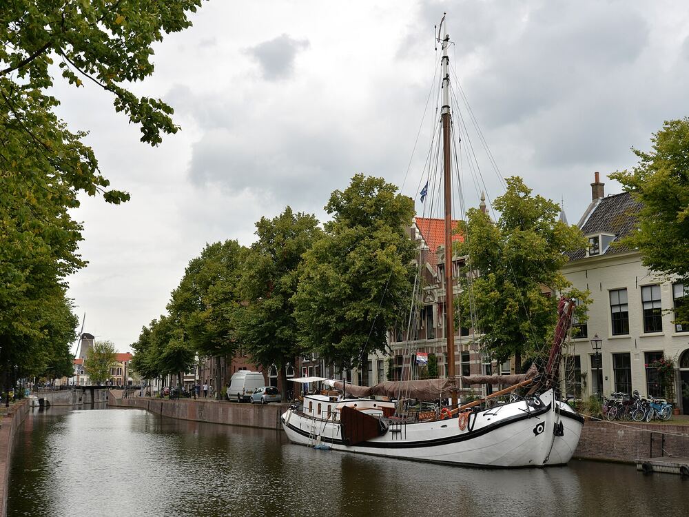 Een gracht in Schiedam met een zeilschip en bomen langs de kade